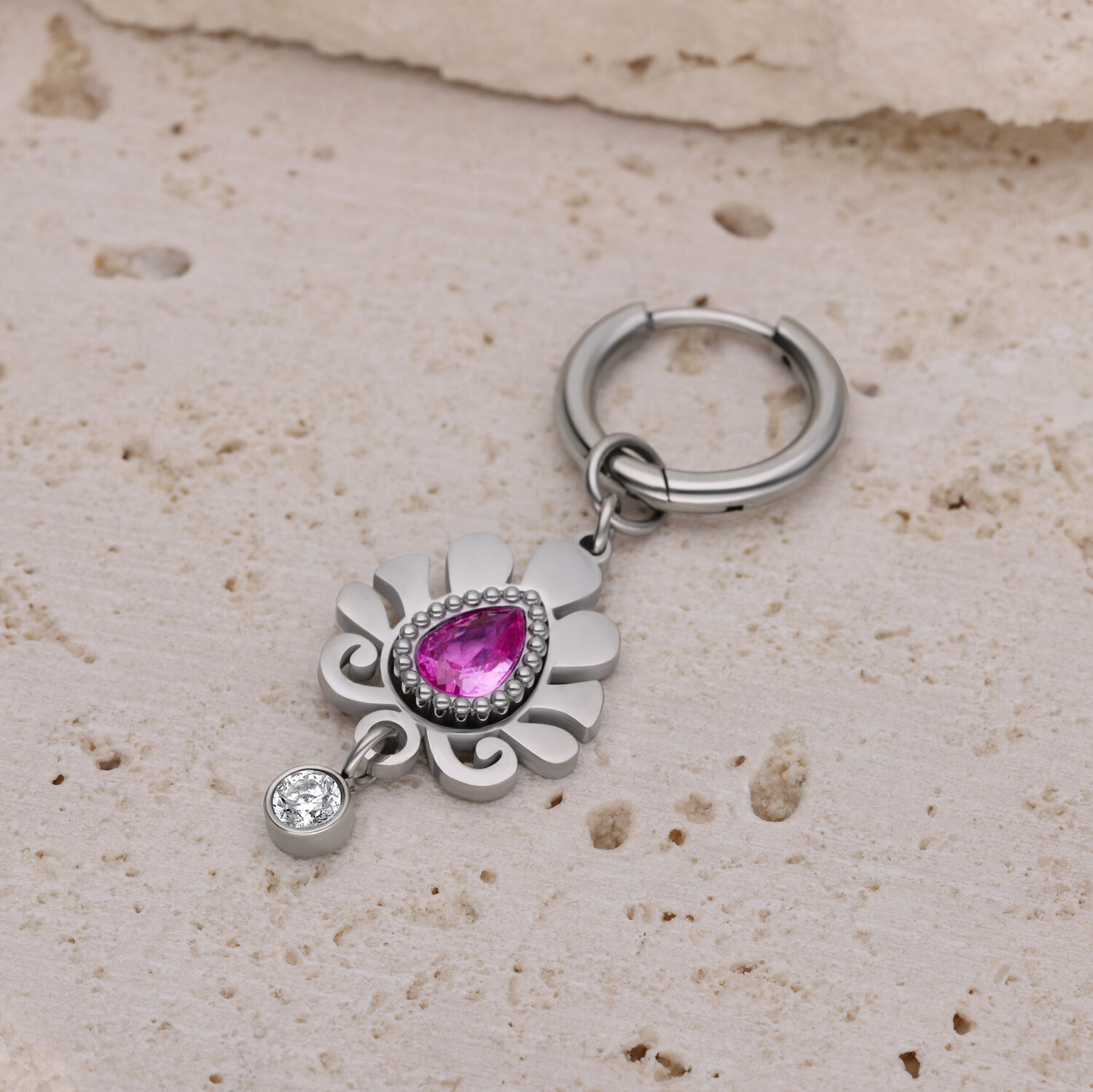 Créole argentée avec pendentif rose Créole argentée avec pendentif rose en forme de goutte sur pierre beige