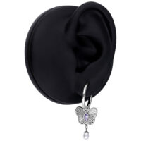 Boucles d'oreilles argentées avec design papillon Boucle d'oreille argentée avec pendentif papillon violet et perle sur un modèle d'oreille noir