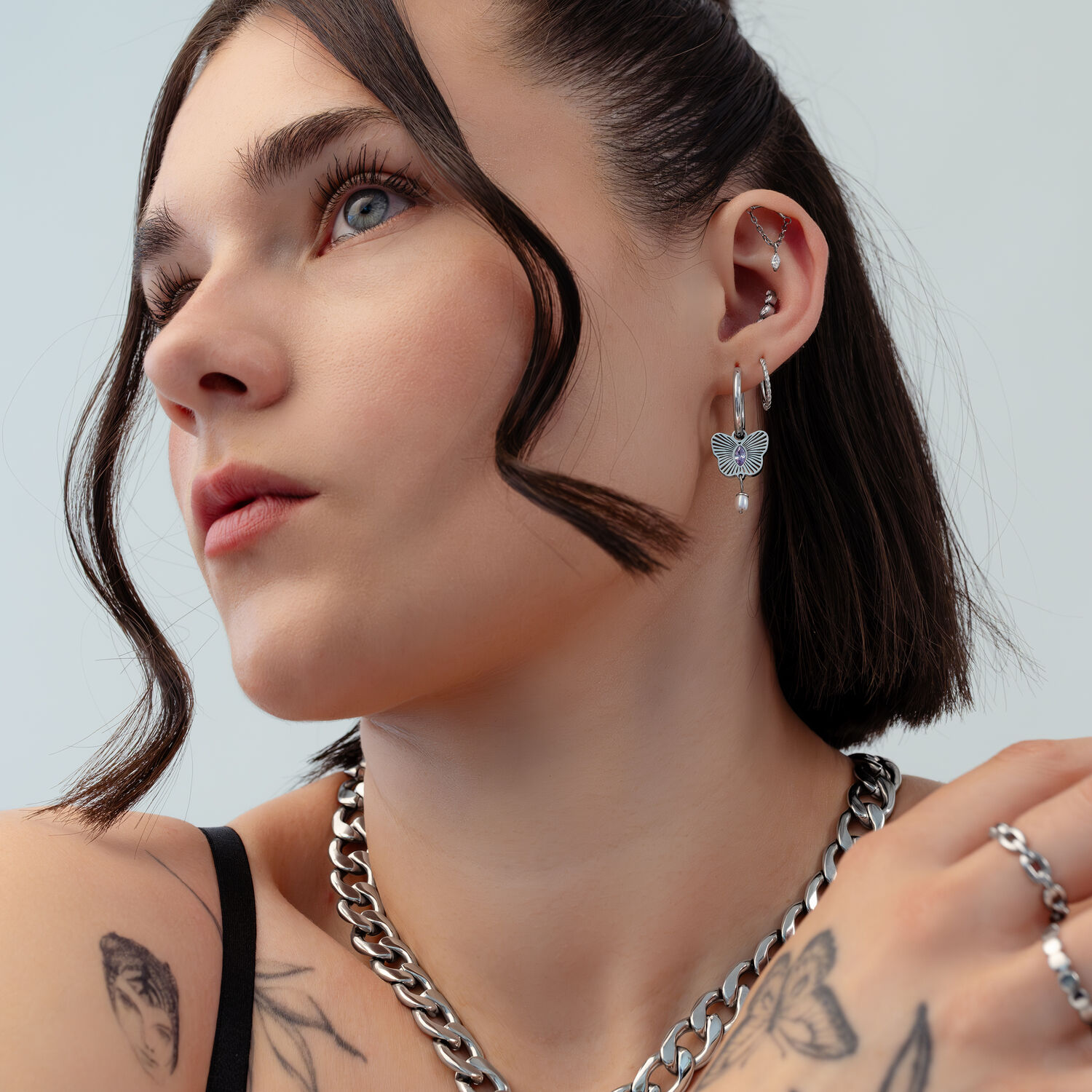 Boucles d'oreilles créoles papillon argentées Femme avec des boucles d'oreilles créoles papillon argentées, gros plan