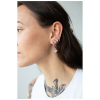 Créoles Little Polar Star argentées à l'oreille Femme portant des boucles d'oreilles argentées avec pendentif étoile sur fond blanc