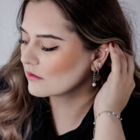 Femme avec boucles d'oreilles Monstera en acier inoxydable, couleur argentée, vue de côté