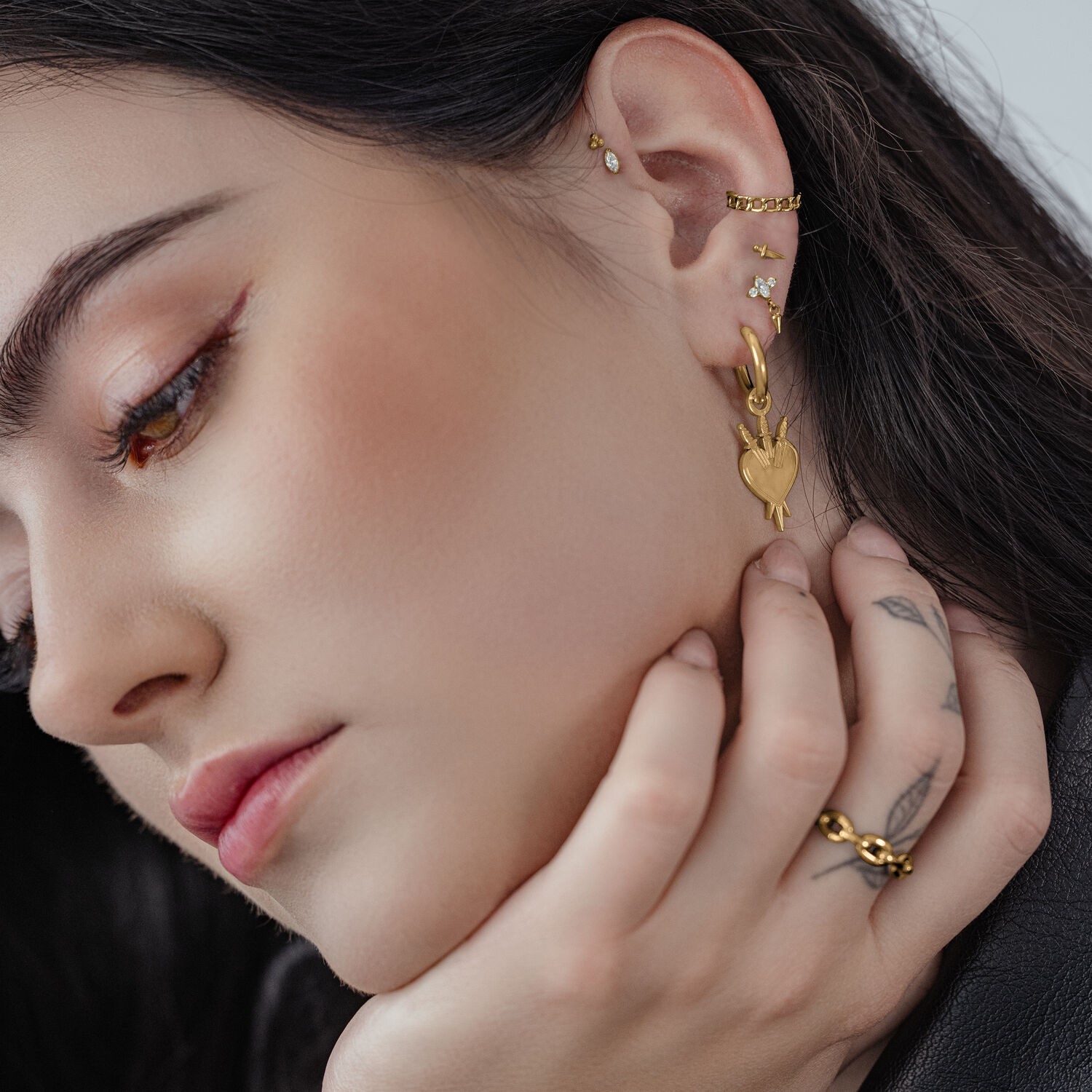 Créoles Cœur Dorées en Acier Chirurgical Gros plan sur des créoles cœur dorées à l'oreille d'une femme aux cheveux foncés