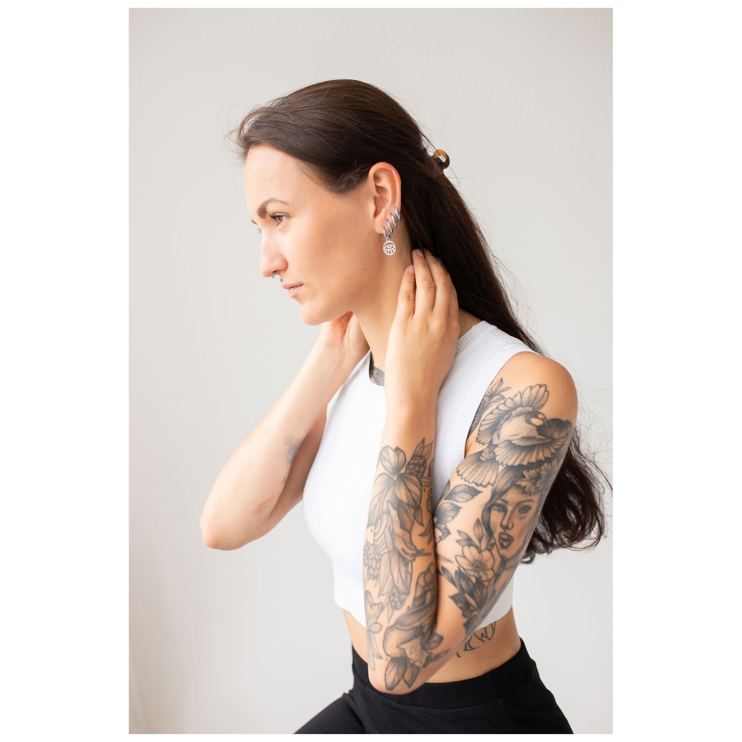 Little Eye Hoops portés par une femme Femme aux longs cheveux et tatouages portant des boucles d'oreilles Little Eye Hoops