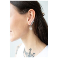 Petites créoles Little Eye argentées portées à l'oreille Femme avec des petites créoles Little Eye argentées dans plusieurs piercings, profil latéral