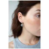 Boucles d'oreilles Little Luminous Eye Hoops argentées Femme portant des boucles d'oreilles argentées avec motif œil, vue de côté