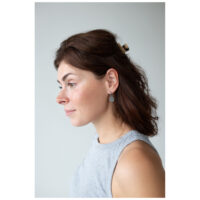 Little Luminous Eye Hoops portés à l'oreille Femme aux cheveux bruns portant les Little Luminous Eye Hoops, vue de côté