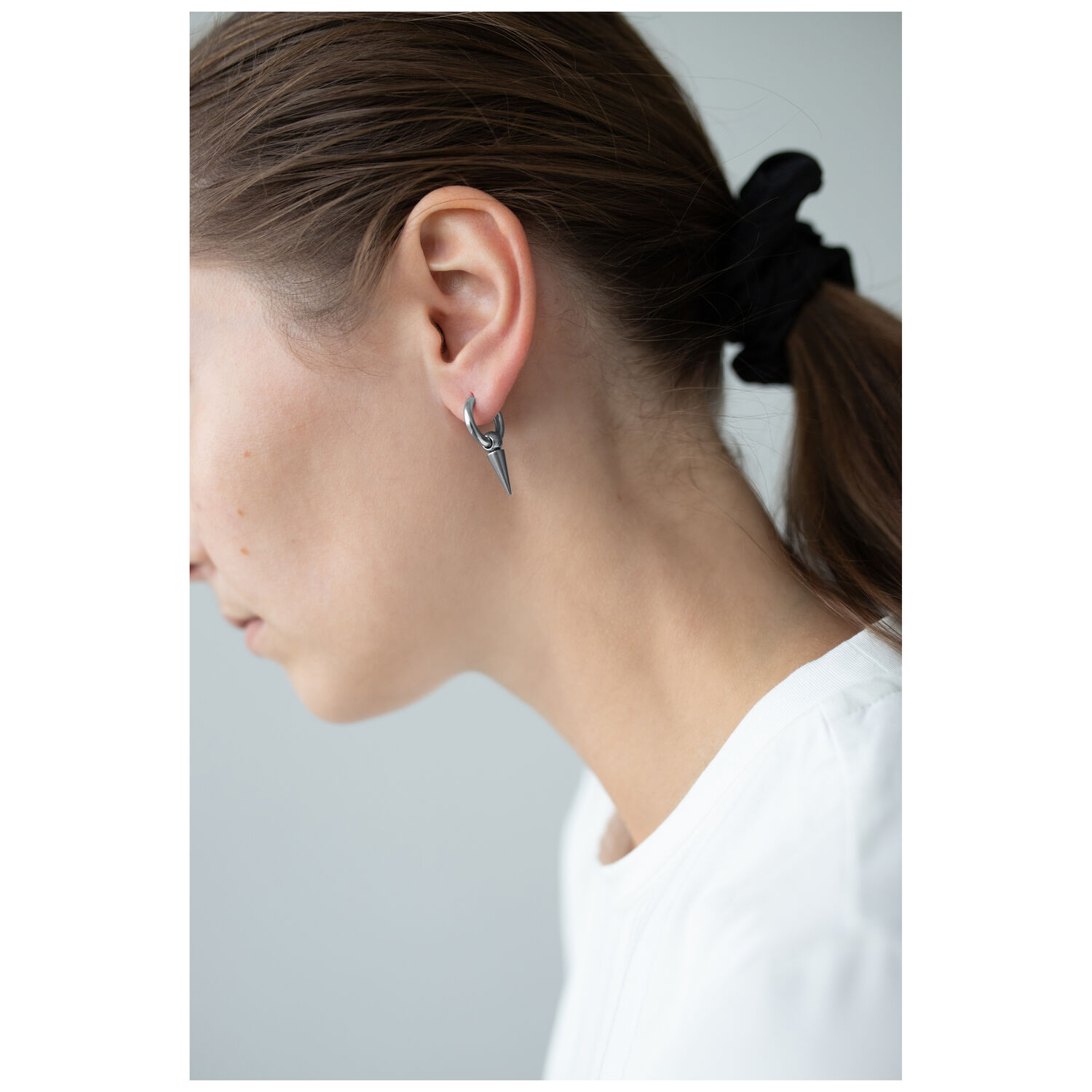 Élégants boucles d'oreilles Spike en argent Femme avec boucles d'oreilles Spike en argent, cheveux en queue de cheval, fond blanc