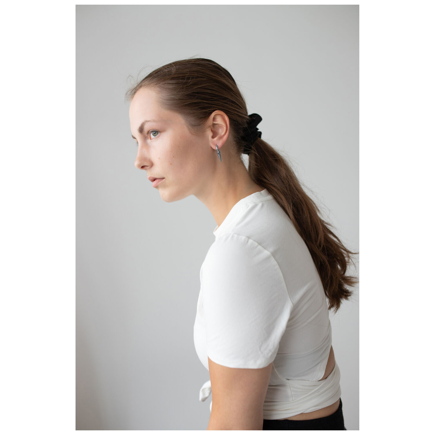 Élégantes boucles d'oreilles Spike en noir et argent Femme aux cheveux longs et lisses portant des boucles d'oreilles Spike en acier chirurgical noir et argent, haut blanc.