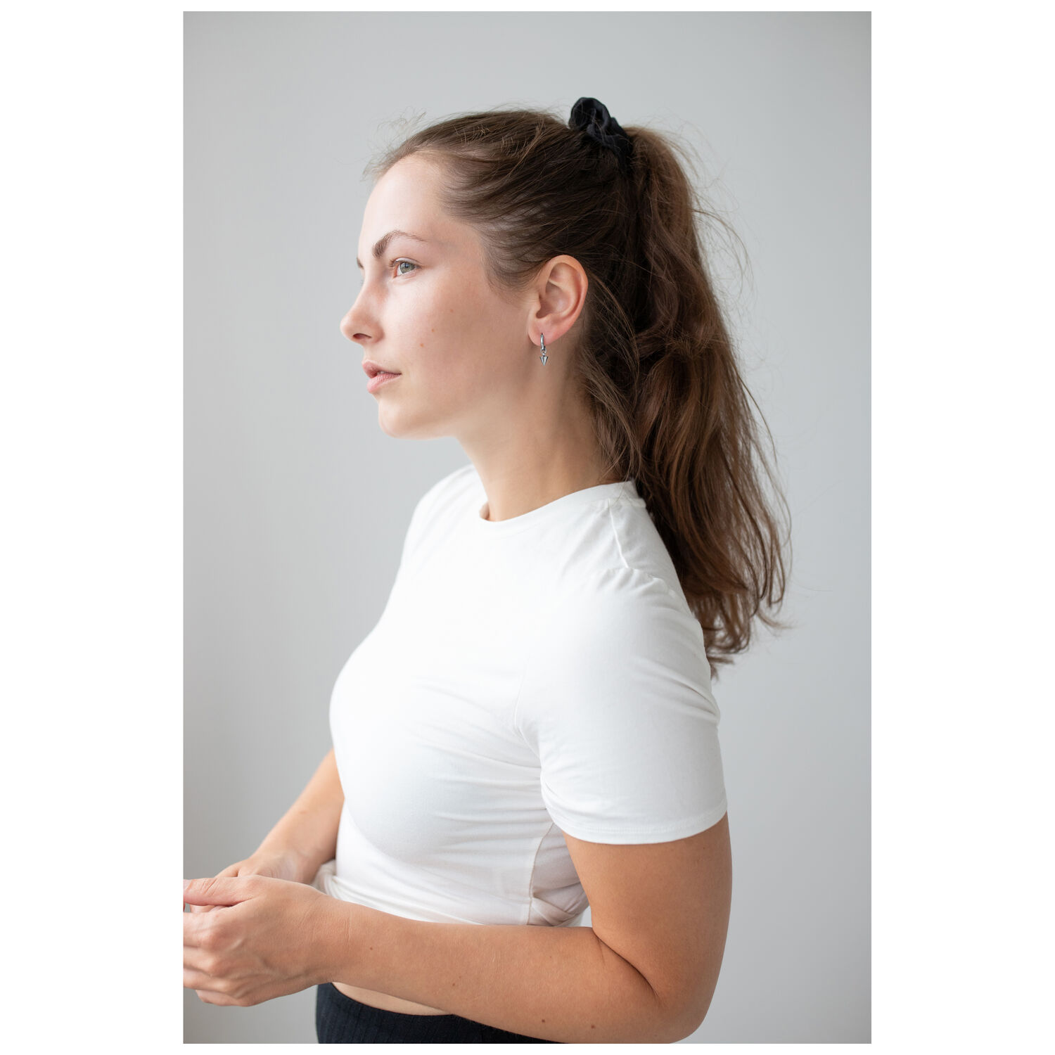 Élégantes créoles courtes à pointes noires Femme aux longs cheveux portant des créoles à pointes noires sur fond gris
