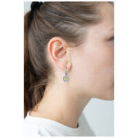 Boucles d'oreilles Daisy argentées portées à l'oreille Boucles d'oreilles argentées en forme de marguerite sur une oreille avec des cheveux bruns