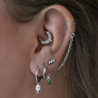 Little Tear Hoops en noir et vert émeraude Plusieurs boucles d'oreilles dans l'oreille, y compris des Little Tear Hoops noires avec cristal vert.