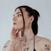 Créoles élégantes en acier inoxydable noir et argent Femme avec des créoles noires et argentées, photographiée de côté