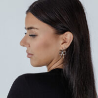 Boucles d'oreilles Little Twisted Bow en argent élégantes Femme avec des boucles d'oreilles Little Twisted Bow en argent sur fond clair