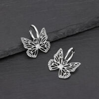 Boucles d'oreilles papillon élégantes en acier inoxydable Deux boucles d'oreilles papillon en argent en acier inoxydable sur fond noir