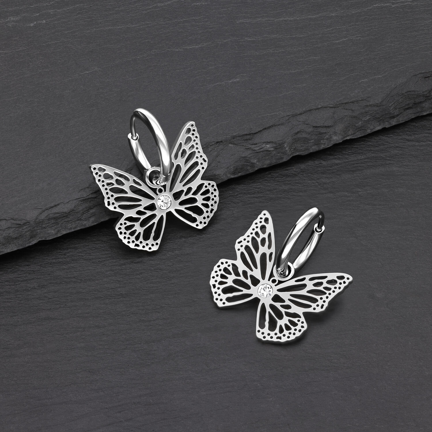 Boucles d'oreilles papillon élégantes en acier inoxydable Deux boucles d'oreilles papillon en argent en acier inoxydable sur fond noir
