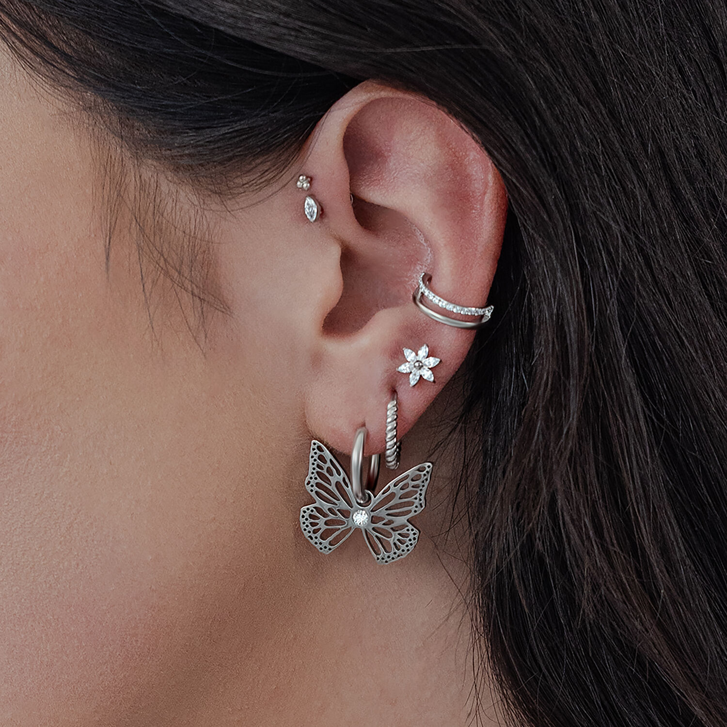 Élégants Little Butterfly Hoops en argent Boucles d'oreilles Little Butterfly Hoops en argent sur l'oreille d'une femme, avec d'autres clous d'oreilles
