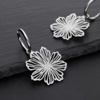 Boucles d'oreilles élégantes en forme de fleurs en acier inoxydable Deux boucles d'oreilles argentées avec motif floral sur fond noir