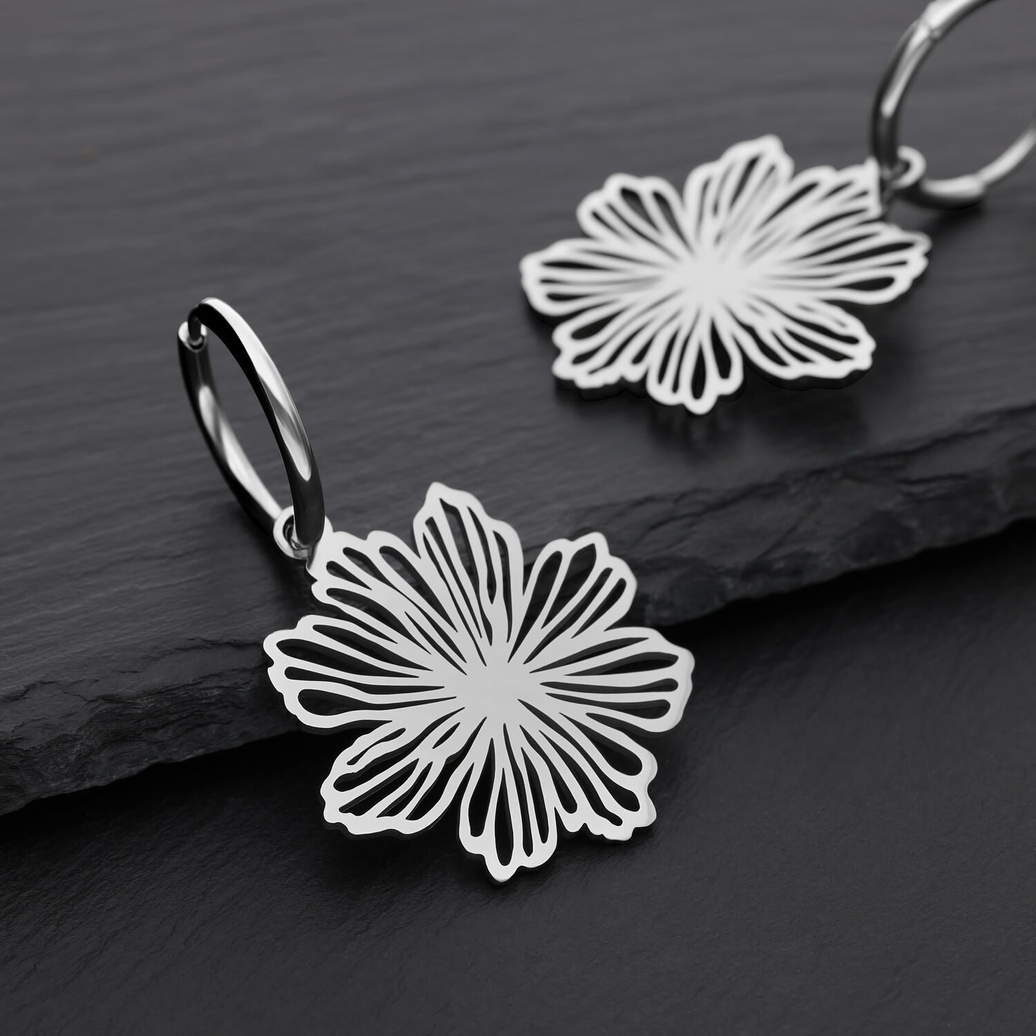 Boucles d'oreilles élégantes en forme de fleurs en acier inoxydable Deux boucles d'oreilles argentées avec motif floral sur fond noir