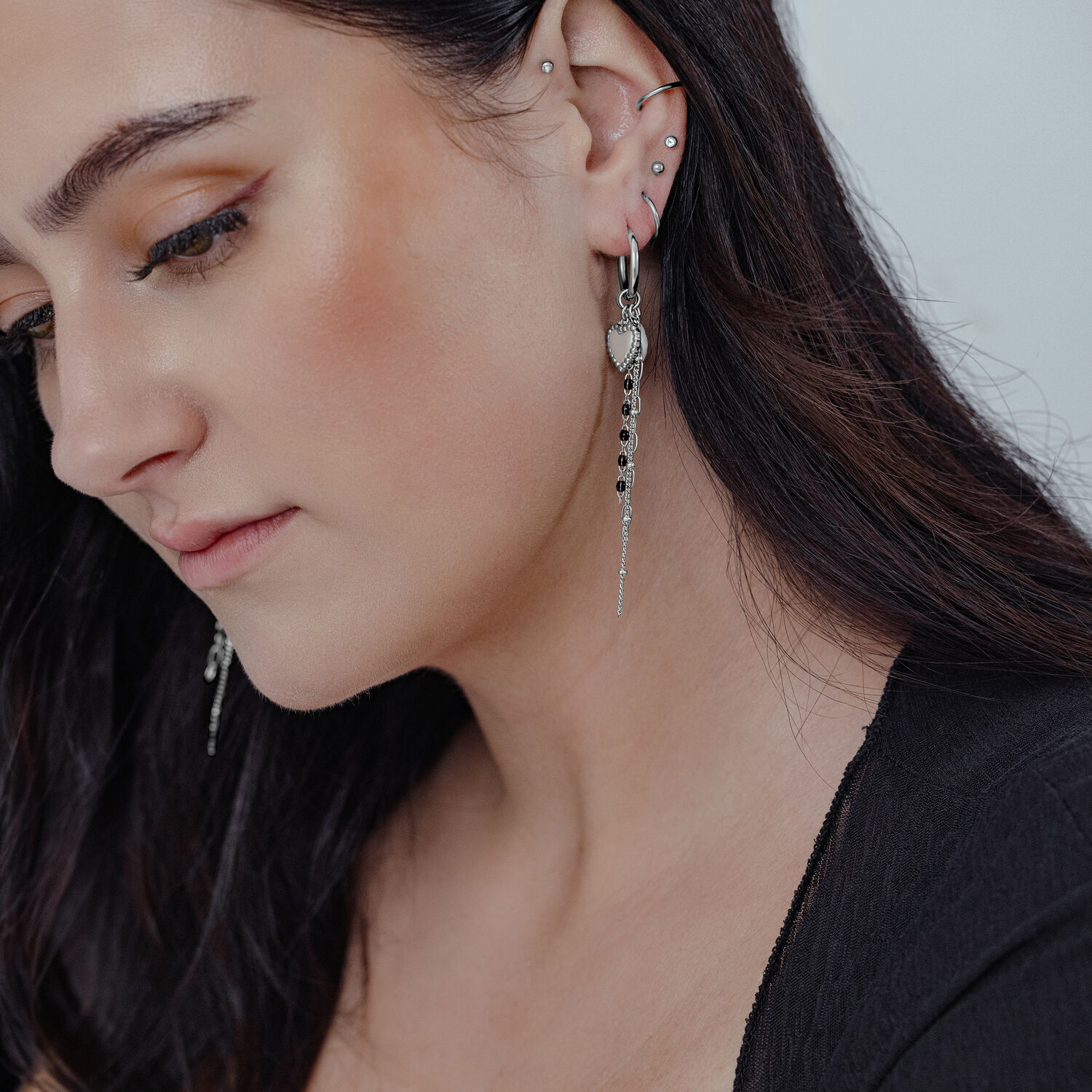 Créoles Bubble Heart avec perle, portées à l'oreille Femme aux cheveux longs et foncés portant des créoles Bubble Heart argentées avec perle à l'oreille