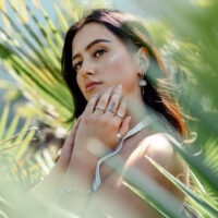 Little Petticoat Hoops au look naturel Femme avec des boucles d'oreilles Little Petticoat Hoops devant des feuilles vertes