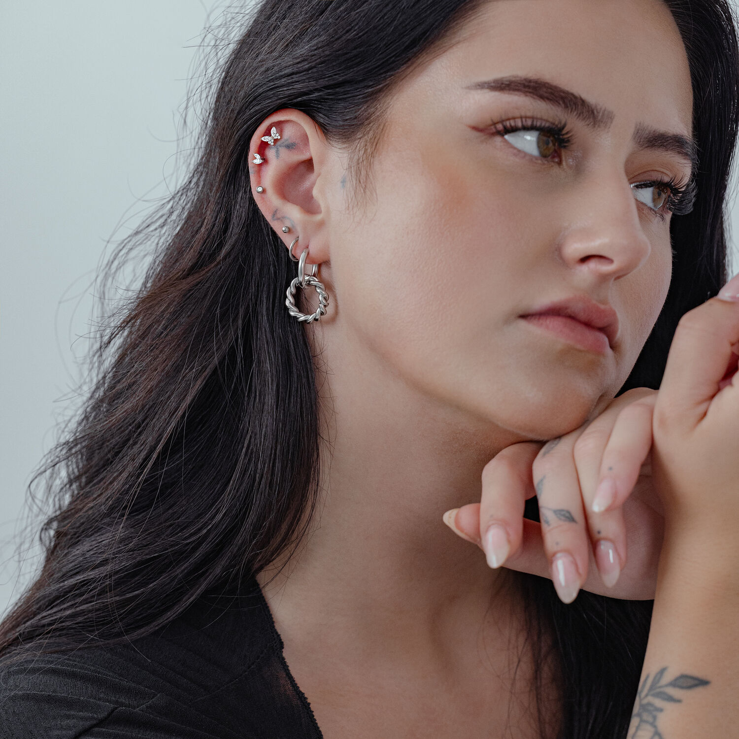 Femme aux longs cheveux portant des Twisted Circle Hoops en argent, profil latéral