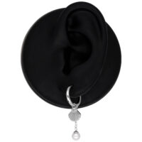 Boucles d'oreilles pendantes argentées avec design coquillage et perle sur présentoir noir