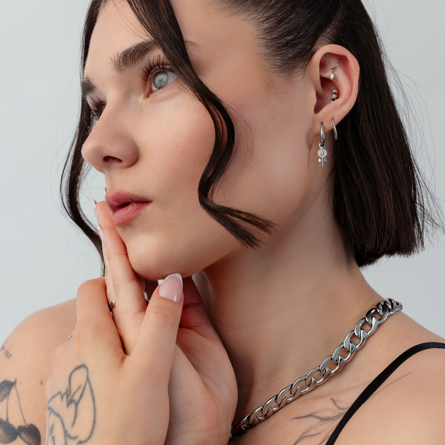 Mini Lollipop créoles en acier inoxydable Femme avec mini créoles Lollipop, cheveux courts, tatouages, fond blanc