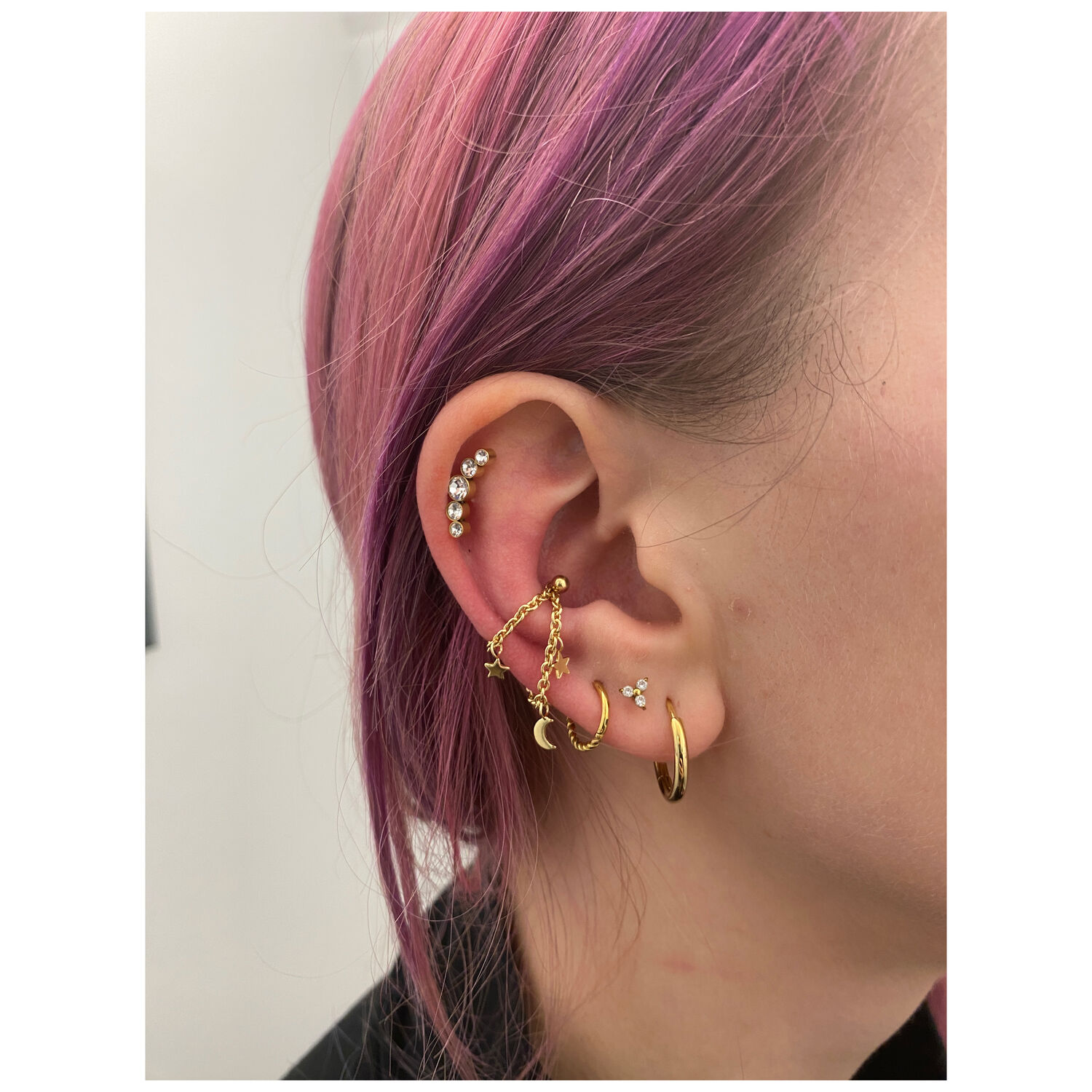 Chaîne de piercing en or avec motifs de lune et d'étoiles portée à l'oreille