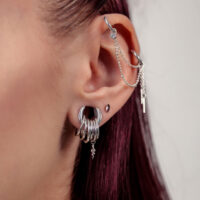 Chaîne de piercing argentée à l'oreille avec chaînes Gros plan d'une oreille avec une chaîne de piercing argentée et plusieurs anneaux argentés