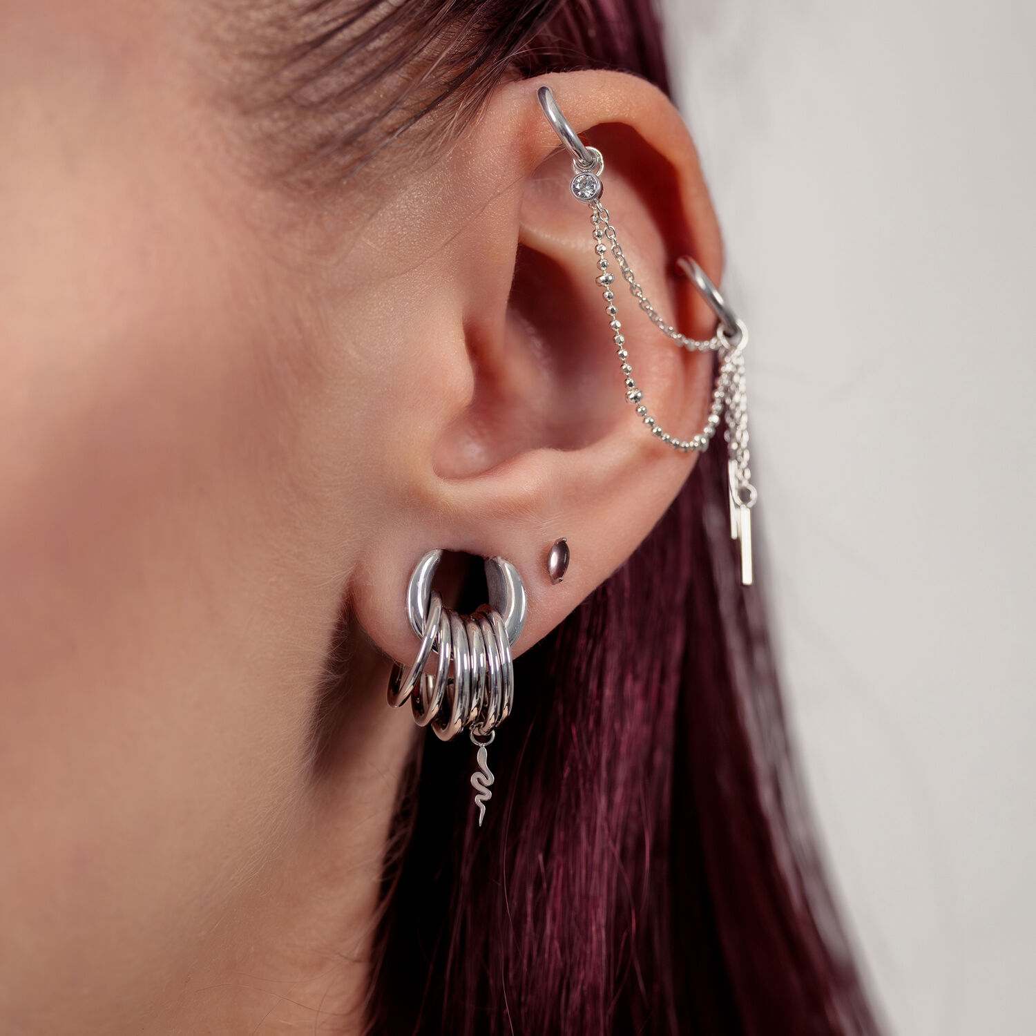 Chaîne de piercing argentée à l'oreille avec chaînes Gros plan d'une oreille avec une chaîne de piercing argentée et plusieurs anneaux argentés