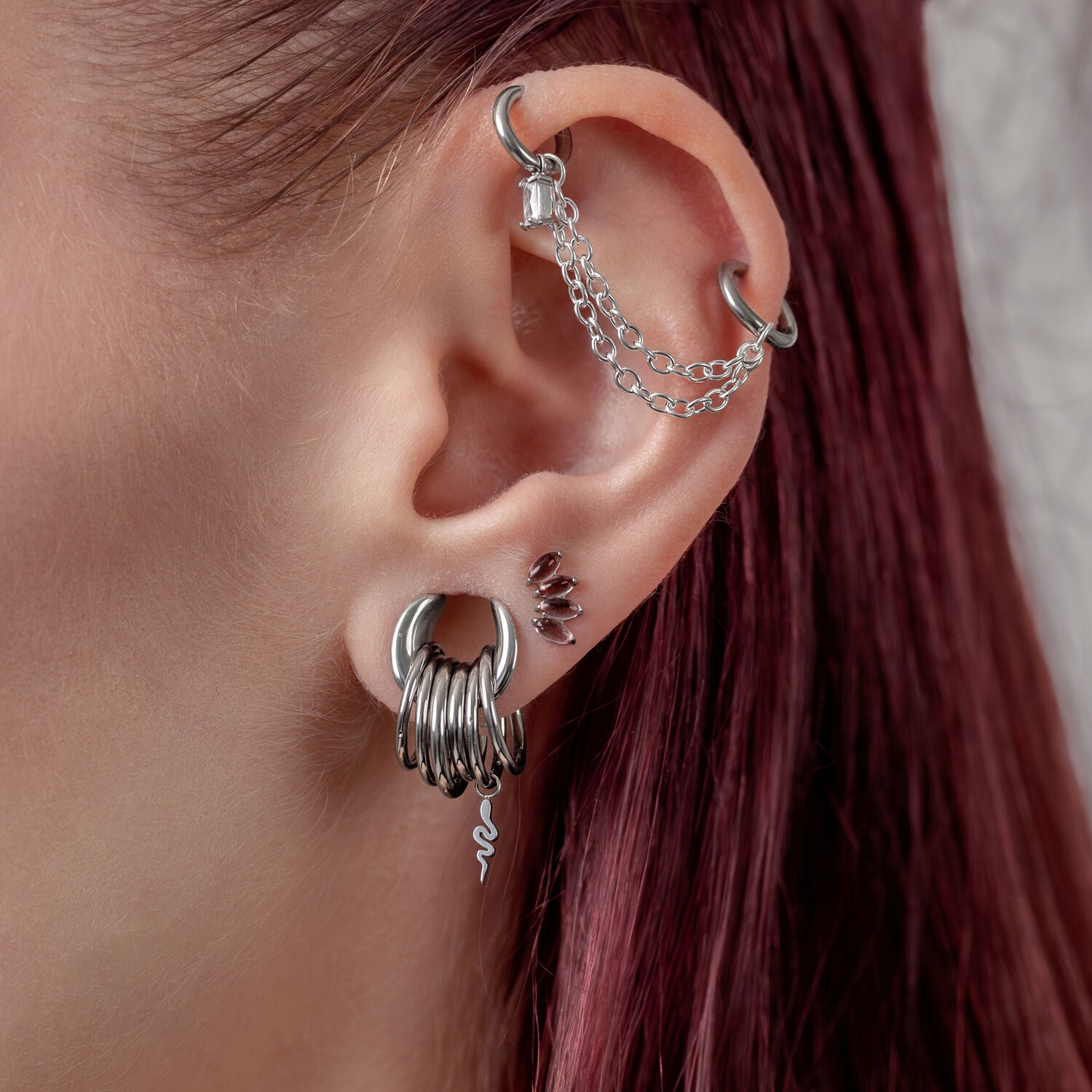 Chaîne de piercing double en argent Oreille avec plusieurs piercings en argent et une chaîne sur fond blanc
