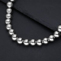Collier Bubble argenté en acier chirurgical Gros plan d'un collier argenté en boules métalliques brillantes sur fond sombre