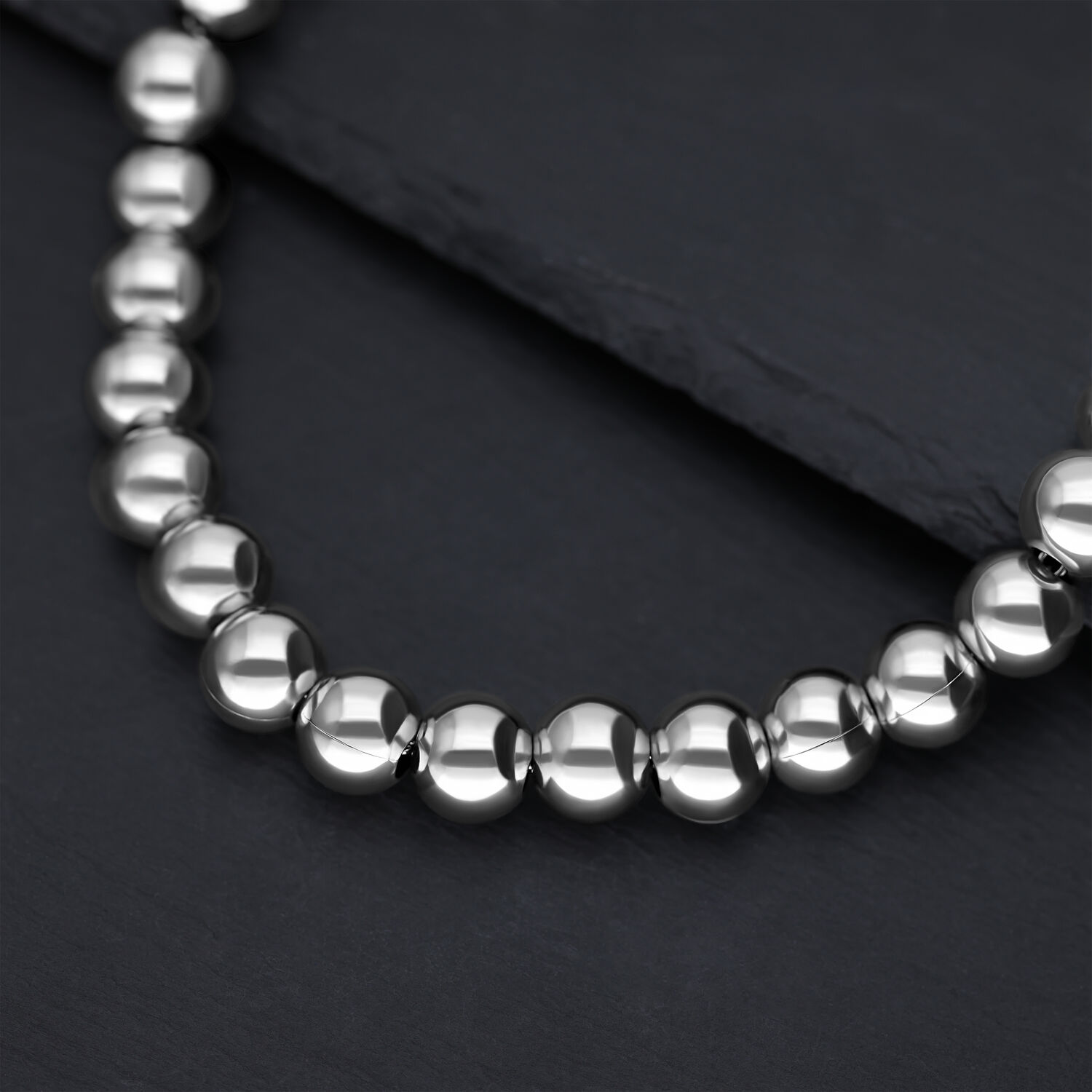 Collier Bubble argenté en acier chirurgical Gros plan d'un collier argenté en boules métalliques brillantes sur fond sombre