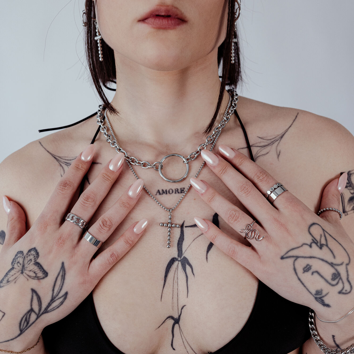 Femme avec le collier Wildcat O en acier chirurgical, tatouages et bagues