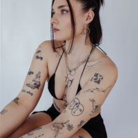Femme avec collier O doré en acier chirurgical, tatouages visibles