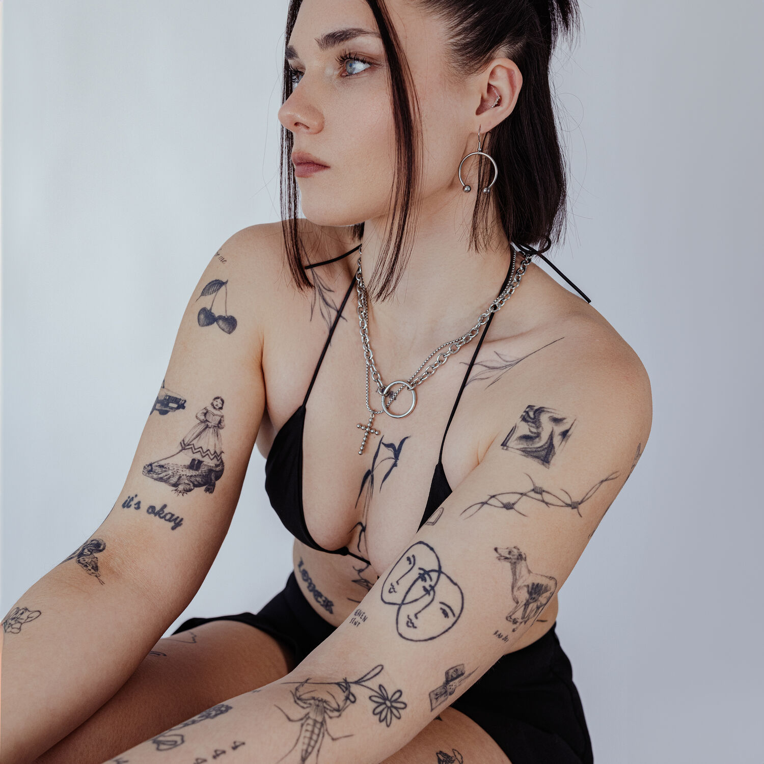 Femme avec collier O doré en acier chirurgical, tatouages visibles