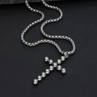 Collier croix argenté avec design à bulles sur fond noir