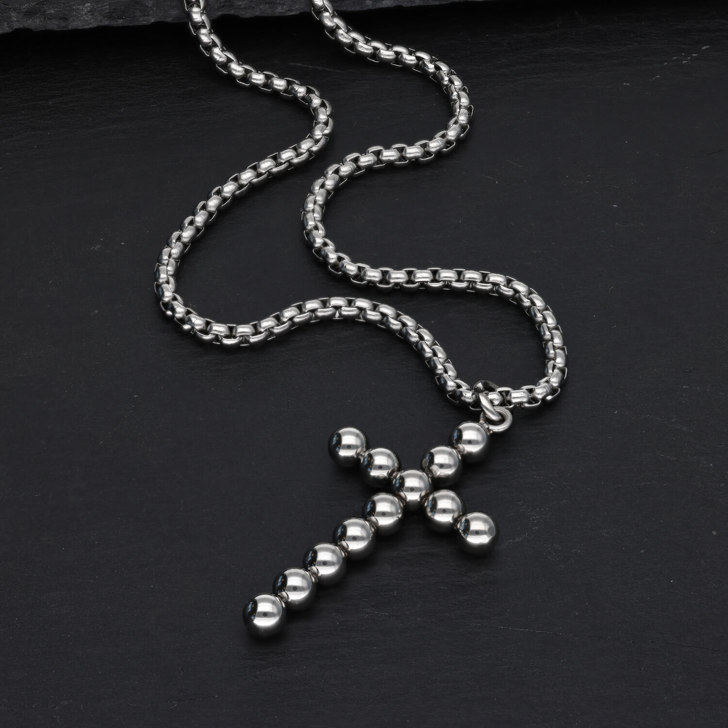 Collier croix argenté avec design à bulles sur fond noir