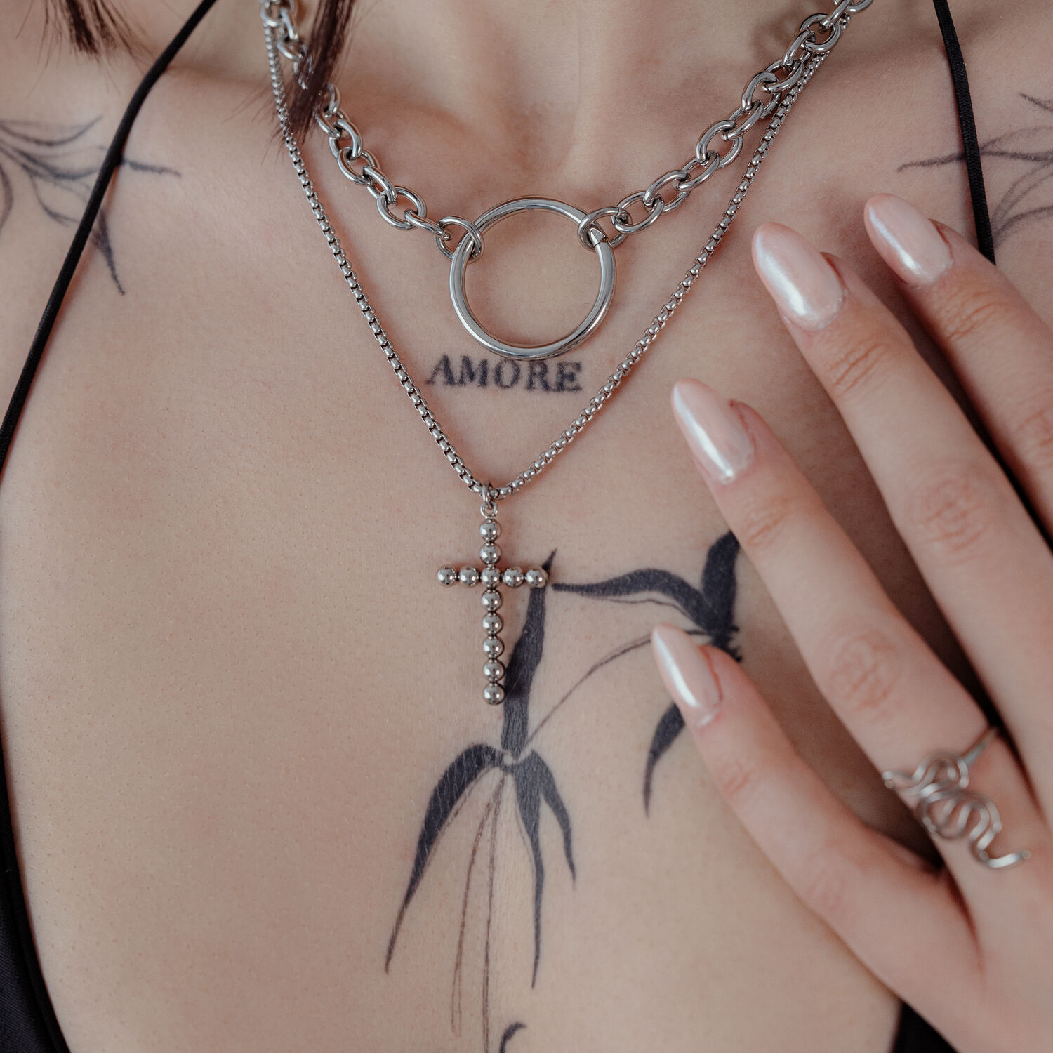 Collier Bubble Cross en argent sur une femme tatouée, gros plan