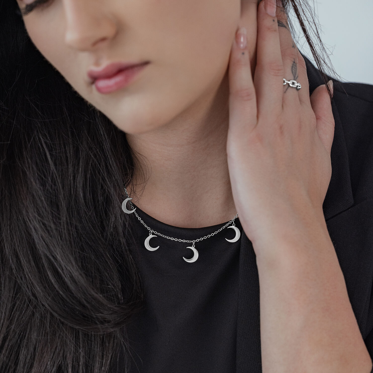Collier Little Moon argenté avec pendentifs Femme portant un collier Little Moon argenté avec plusieurs pendentifs lune sur un haut noir