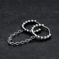 Anneaux Huggie à Double Perle en Acier Chirurgical Deux anneaux Huggie noirs reliés avec des perles sur fond sombre