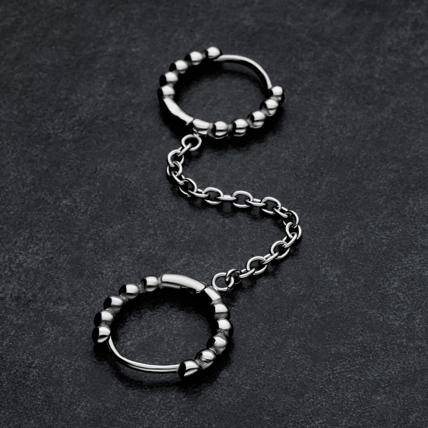 Double Huggie Ball Hoops en argent Double Huggie Ball Hoops en argent avec chaîne sur fond sombre