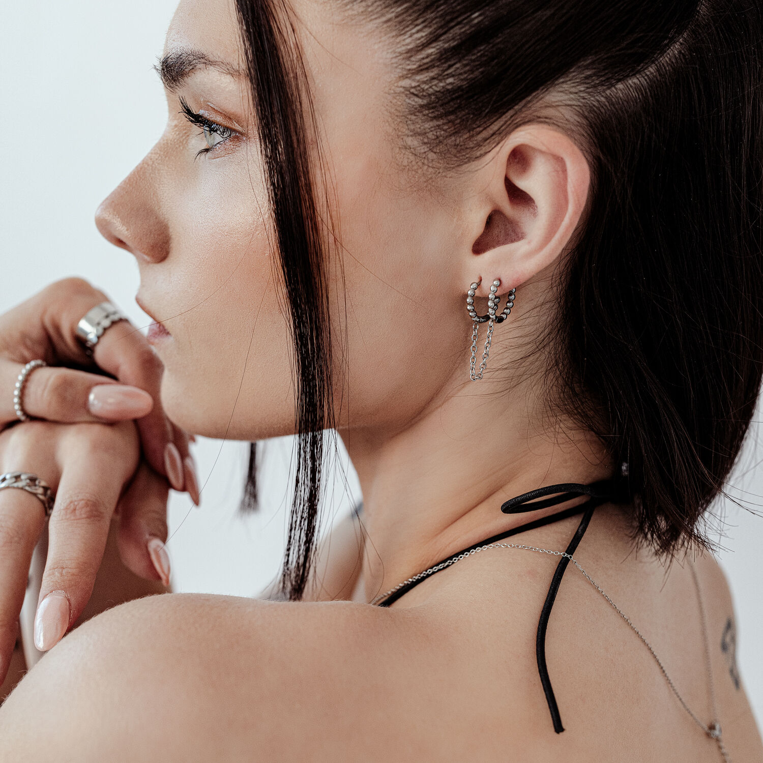 Double Huggie Ball Hoops en noir et argent Gros plan d'une oreille avec des Double Huggie Ball Hoops noirs et argent sur fond clair
