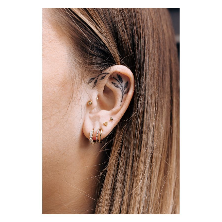 Triangle Barbell en or à l'oreille Piercing Triangle Barbell en or à l'oreille d'une personne avec d'autres piercings et un tatouage à l'oreille