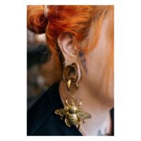 Clicker double cristal doré dans l'oreille Piercing clicker doré dans l'oreille d'une personne aux cheveux rouges et tatouage