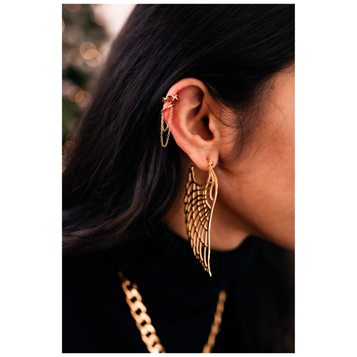 Chaîne d'oreille dorée avec design aile Gros plan d'une oreille avec chaîne dorée et boucle d'oreille aile, portée par une personne