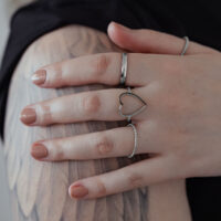 Bague cœur bicolore en acier chirurgical Bague cœur en argent en acier chirurgical sur une main avec bras tatoué