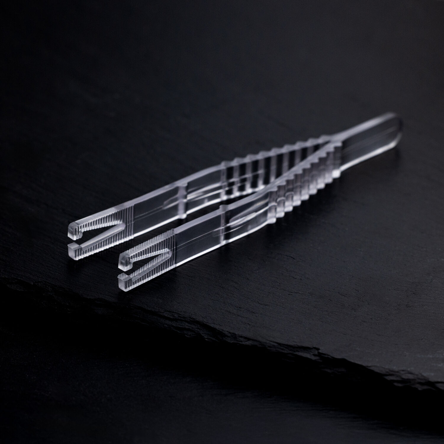 Pince à piercing triangulaire stérile sur fond noir Pince à piercing triangulaire stérile claire sur fond noir, emballée individuellement