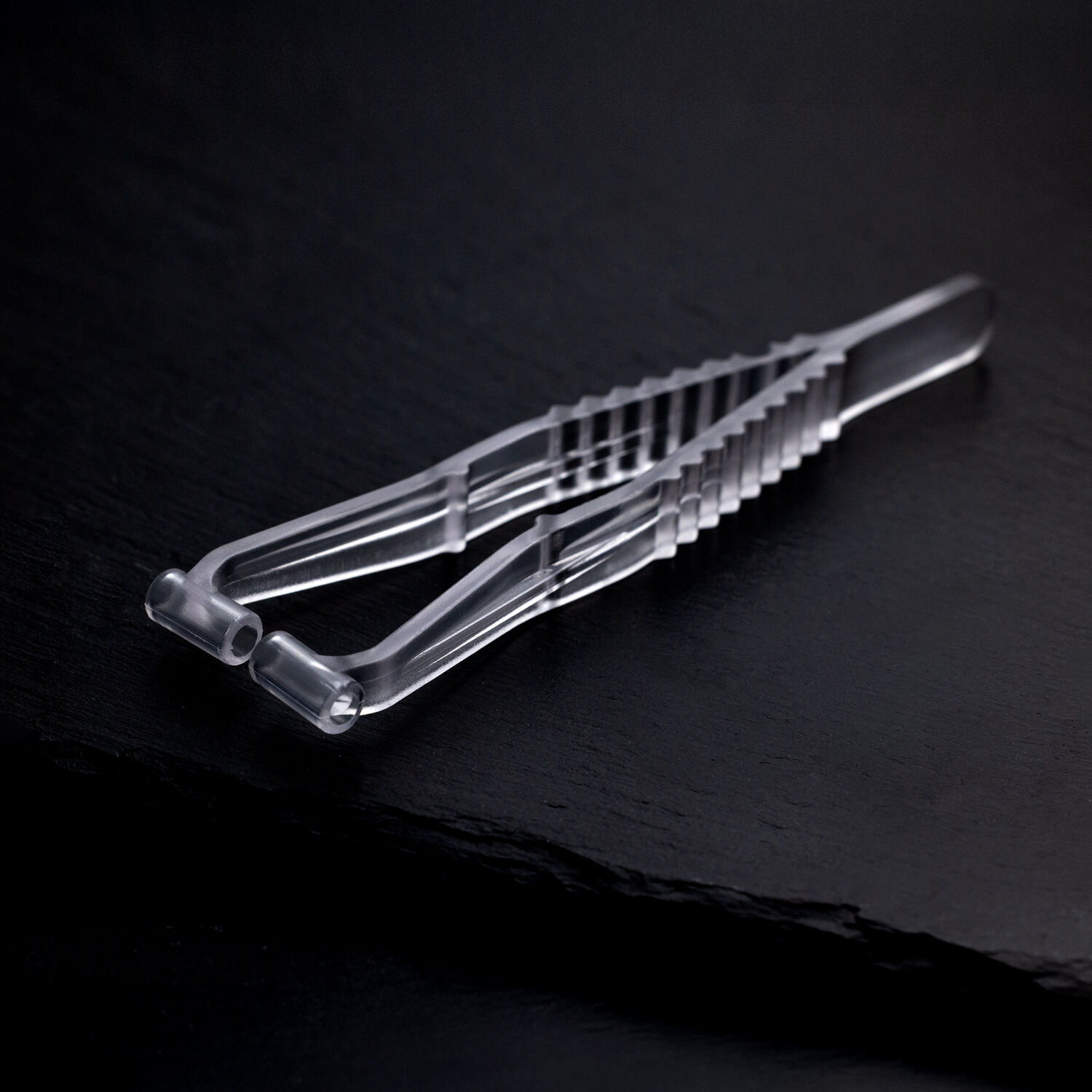 Pince à septum stérile sur fond noir Pince à septum transparente en plastique sur fond sombre et lisse