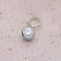 Pendentif rond en cristal en acier chirurgical Pendentif rond en cristal argenté en acier chirurgical sur fond beige
